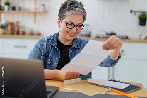 Stampa su tela Cheerful smiling mature woman looking through mail, invitation to event