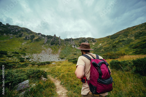 A man in a leather hat, with a backpack, on the path leading to the top of Mount Spitsy, Carpathian Mountains, nature of Ukraine. Tourism and active lifestyle