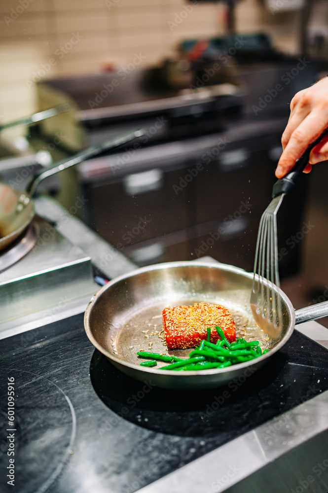 man chef cooking fried tuna fish and green bean in frying pan on kitchen man chef cooking fried tuna fish and green bean in frying pan on kitchen
