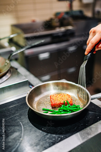 man chef cooking fried tuna fish and green bean in frying pan on kitchen