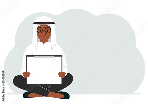 A man sits crossing his legs and holds a clipboard with a white read sheet for the text in his hands.