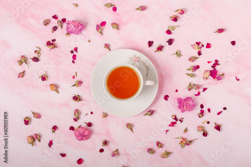 Cup of tea on pink background with flowers. Top view