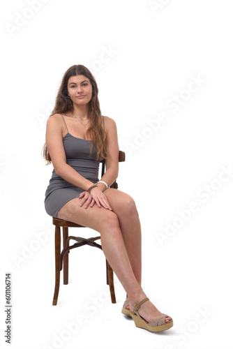 front view of young girl sitting on chair looking at camera on white background