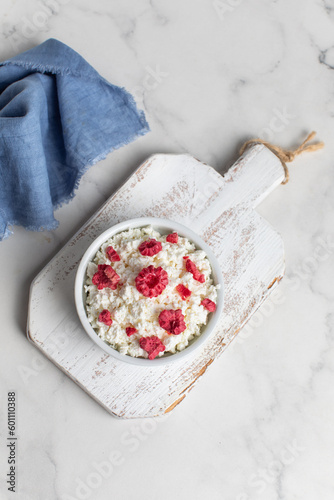 Fresh cottage cheese with raspberries in a bowl on a white background
