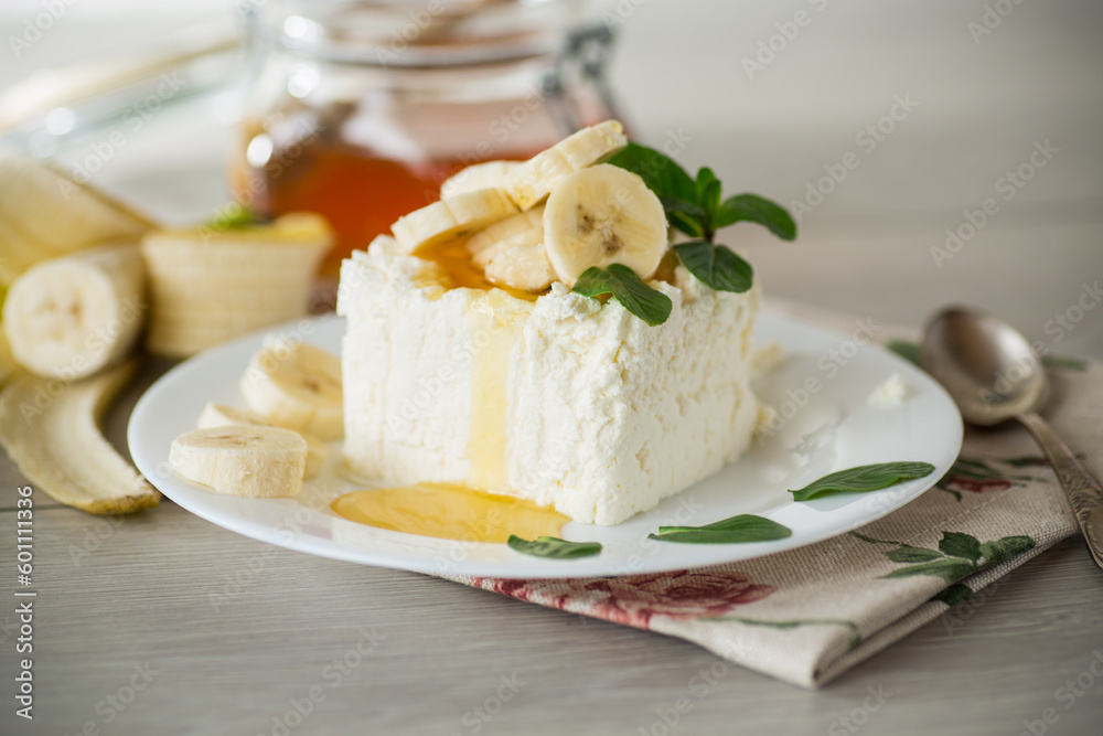 Portion of homemade milk curd with banana slices and honey