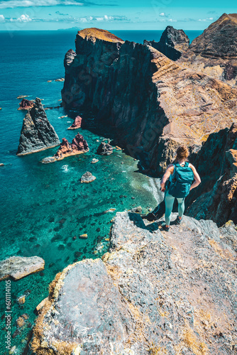 Athletic woman enjoys the view on rocky cliff from a steep cliff. São Lourenço, Madeira Island, Portugal, Europe. © Michael