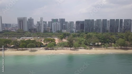 Aerial drone view of East Coast Park Beach revealing the urban buildings in the background - Singapore 2021