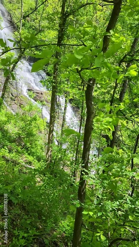 footage of a gorgeous spring landscape with a flowing waterfall over large rocks surrounded by lush green trees and plants at Amicalola Falls State Park in Dawsonville Georgia USA photo