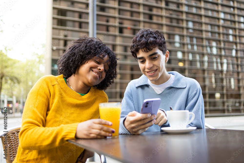 Happy young diverse friends sitting at table in open cafe Happy young diverse friends sitting at table in open cafe
