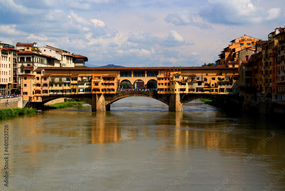 Photo of a view of the Ponte Vecchio arch bridge with houses across the Arno river in the historic center of Florence, Italy