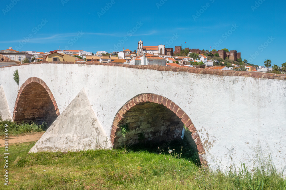 View of the roman-arab-medieval town of Silves with the ancient roman bridge in the foreground, Algarve, Portugal. roman-arab-medieval village 