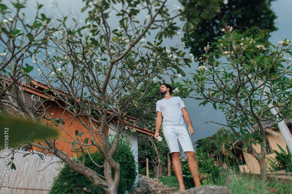 A man in white clothes in a tropical garden A man in white clothes in a tropical garden