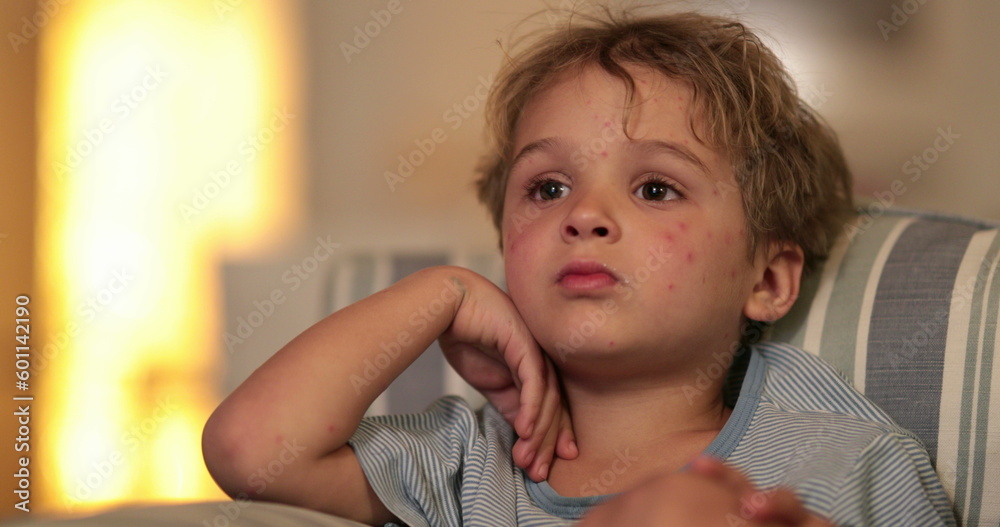 Child boy face watching TV on sofa at night before bed