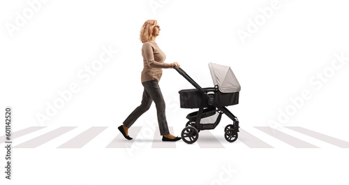 Full length profile shot of a mature woman pushing a baby stroller at a pedestrian crossing © Ljupco Smokovski