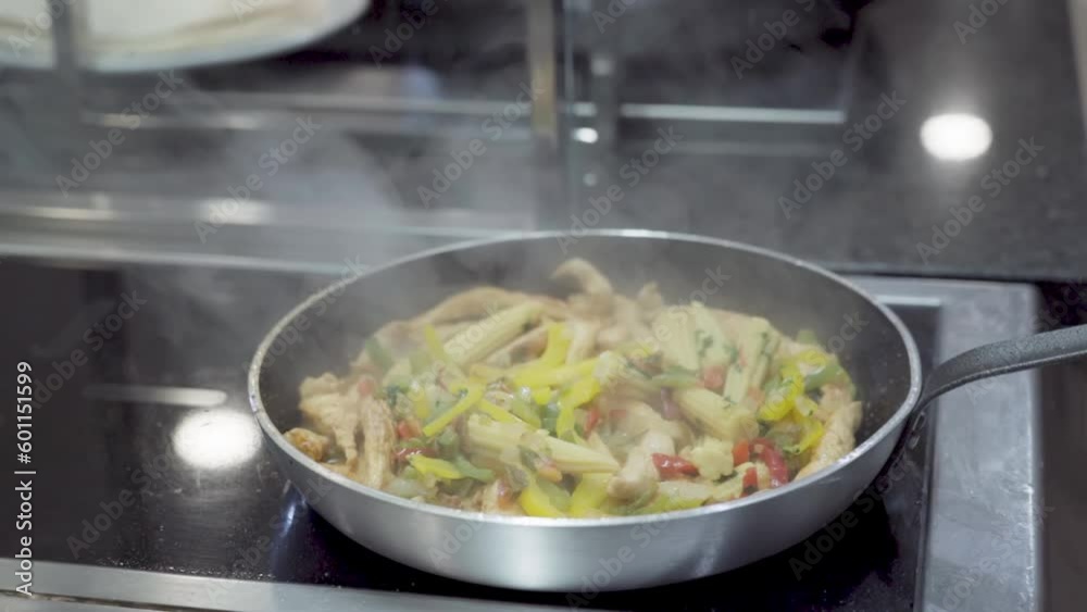 The chef prepares fresh food in a frying pan by steaming the ingredients.