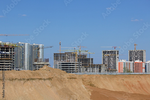 Construction site. Reinforced concrete frames of multi-storey buildings and construction cranes. Against the background of the blue sky.