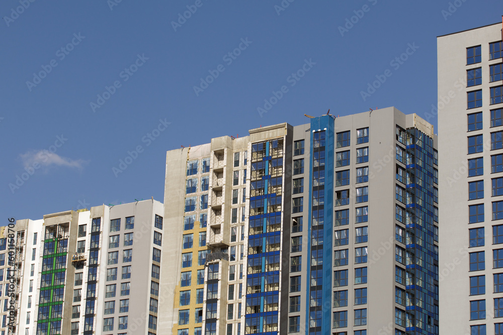 Modern high-rise buildings made of concrete and glass. Color design of facades. Construction site. The final stage of construction. Against the background of the blue sky. Modern high-rise buildings made of concrete and glass. Color design of facades. Construction site. The final stage of construction. Against the background of the blue sky.