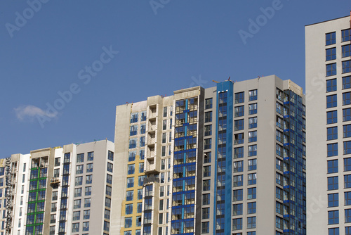 Modern high-rise buildings made of concrete and glass. Color design of facades. Construction site. The final stage of construction. Against the background of the blue sky. © f2014vad
