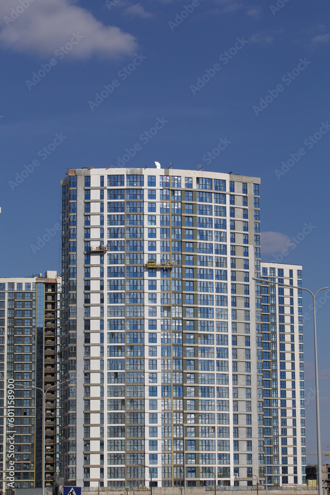 Construction site. Reinforced concrete frames of multi-storey buildings and construction cranes. Finished houses nearby. Against the background of the blue sky.