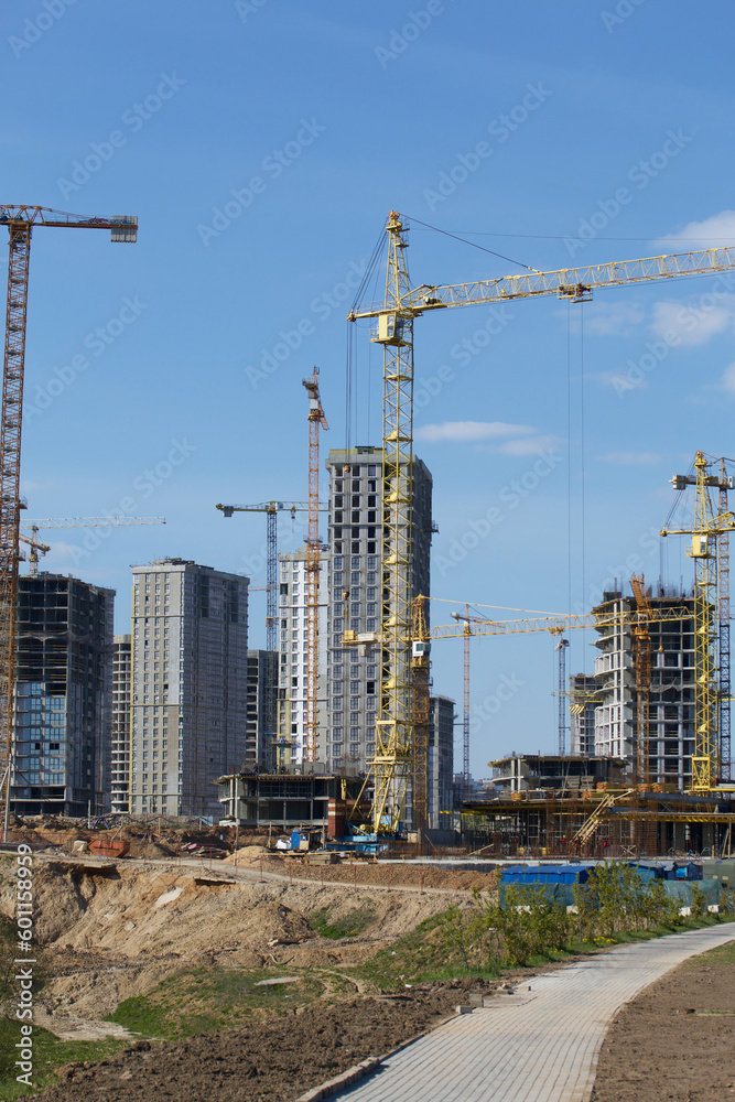 Construction site. Reinforced concrete frames of multi-storey buildings and construction cranes. Against the background of the blue sky. Construction site. Reinforced concrete frames of multi-storey buildings and construction cranes. Against the background of the blue sky.