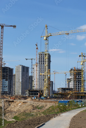 Construction site. Reinforced concrete frames of multi-storey buildings and construction cranes. Against the background of the blue sky.