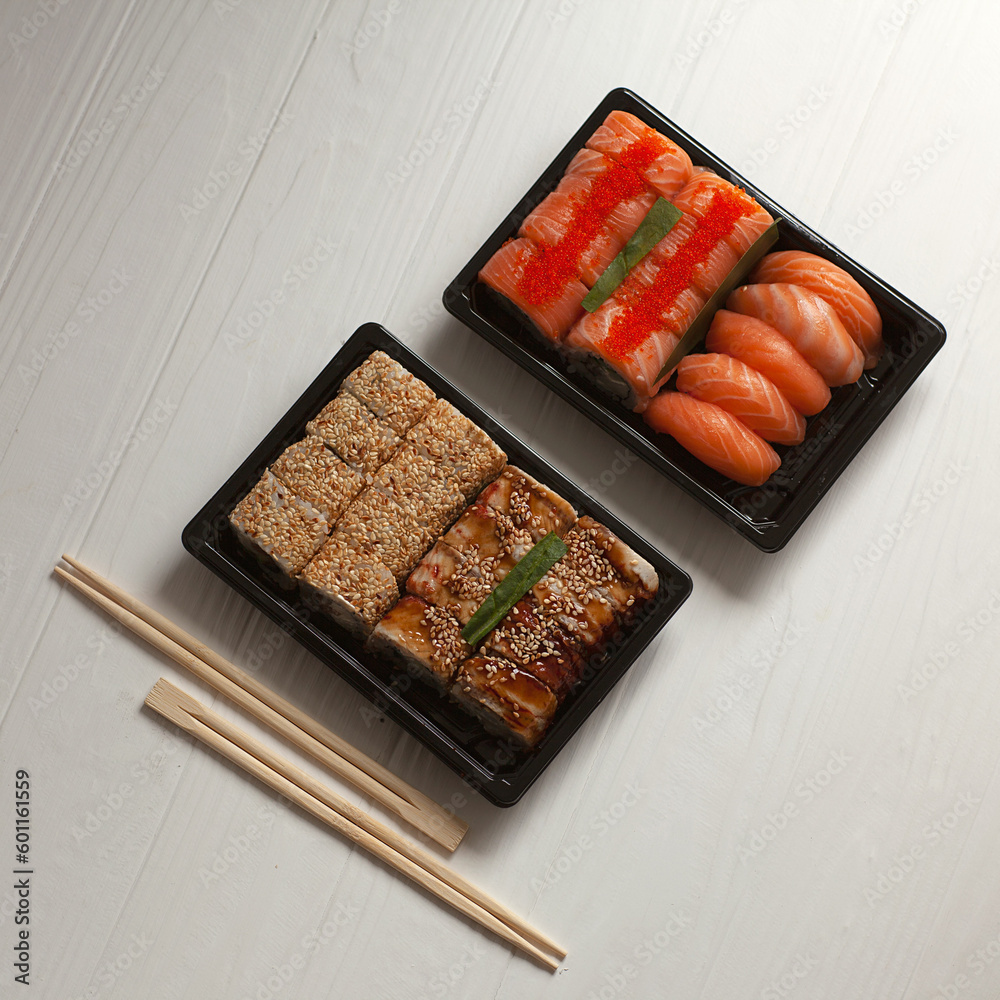 Fast delivery service Japanese food rolls in takeaway packages on a white wooden background. Fast delivery service Japanese food rolls in takeaway packages on a white wooden background.