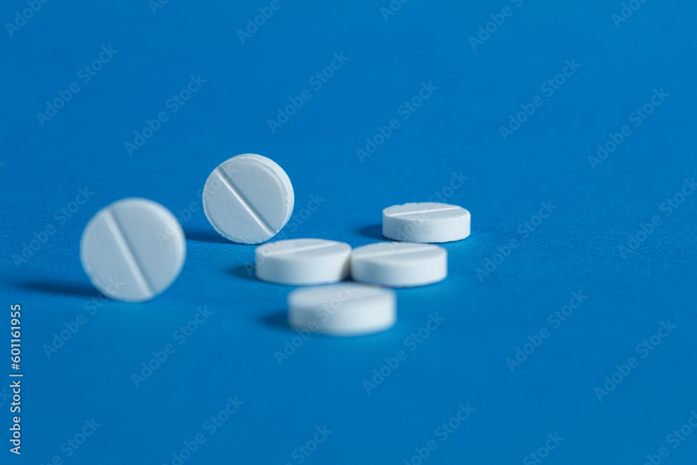 Round white pills, close-up on a blue background