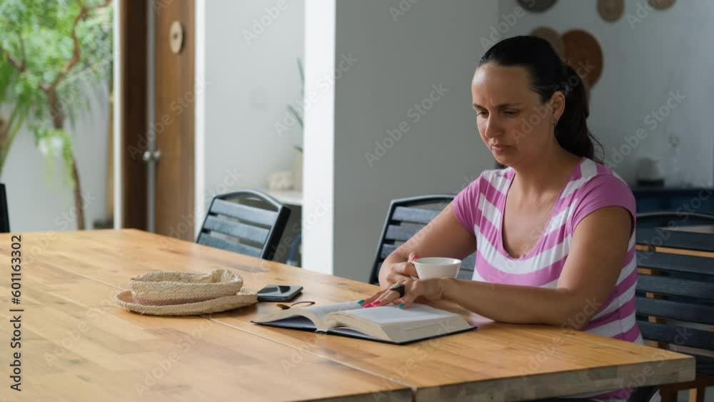 Young woman drinking coffee while reading book at table on terrace Young woman drinking coffee while reading book at table on terrace