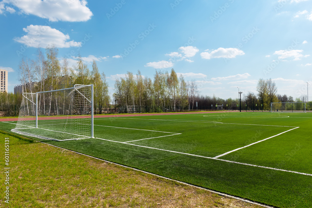 School football, soccer field with artificial turf and goals against a blue sky