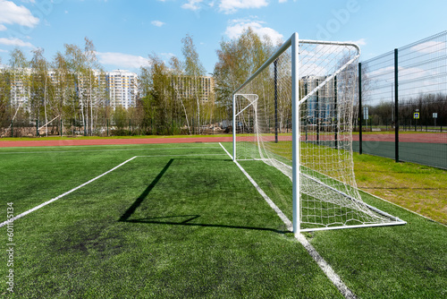 Football goal on a school soccer field with artificial grass against a blue sky