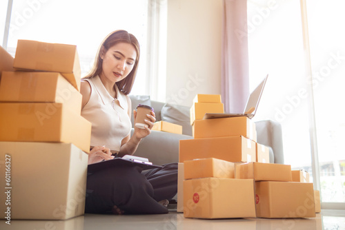 woman checking package of goods from customer online order is alone in her home office as she is an SME entrepreneur and uses her phone and tablet to market online. concept online sales business