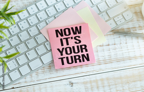 Now it's your turn text, inscription, phrase written in a notebook that lies on a dark table with a laptop and pen. Business concept. photo