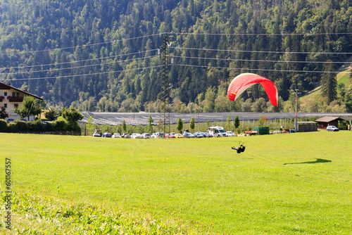Tandem paragliders above apple plantation and mountain panorama near Saltaus, South Tyrol, Italy