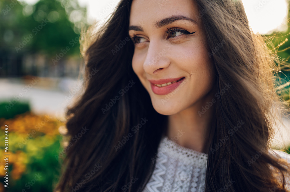 Naklejka premium A boho brunette with lush hair is posing outside on a sunny summer day.