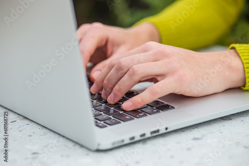 Young satisfied fun happy successful employee business woman 20s she wearing casual yellow shirt hold use laptop pc computer sit work at wooden office desk with pc laptop. Achievement career concept.