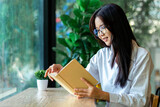 Portrait of Young Asian beautiful woman reading a book while relaxing during work at home.