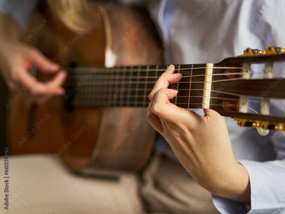 an unrecognizable person playing the spanish guitar playing a chord