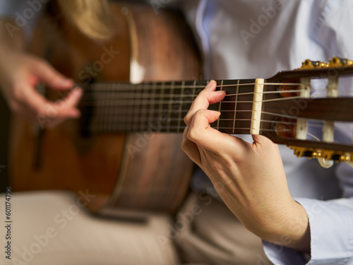 an unrecognizable person playing the spanish guitar playing a chord
