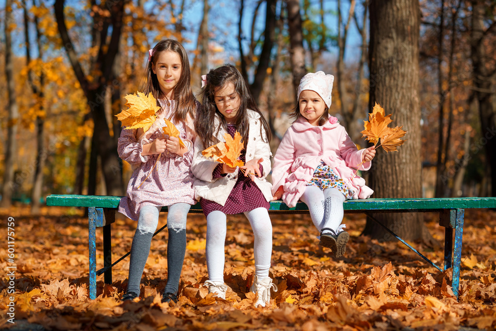 portrait of girls in an autumn city park, children sitting on a bench, talking and enjoying the beautiful nature, talking and playing together, picking yellow leaves portrait of girls in an autumn city park, children sitting on a bench, talking and enjoying the beautiful nature, talking and playing together, picking yellow leaves