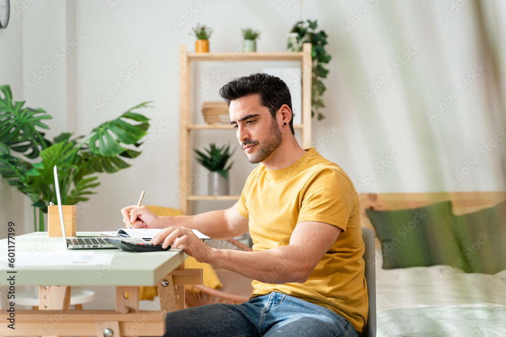Man sitting at desk at home doing bills with calculator. Man sitting at desk at home doing bills with calculator.