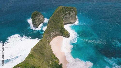 Kelingking sandy beach with tall overgrown rocky cliff and turquoise ocean Nusa Penida Island Bali. Aerial top down view of best tourist destination in Indonesia Asia.