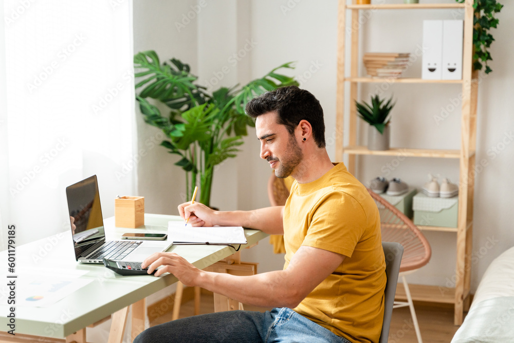 Man sitting at desk at home doing bills with calculator. Man sitting at desk at home doing bills with calculator.