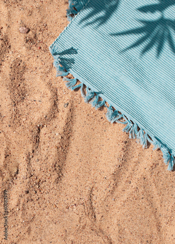 Bright summer beach vacation concept background with tropical leaves shadows and towel on sand. Copy space