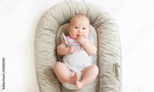 Valokuva Cute caucasian newborn baby girl in the baby nest playing with her feet