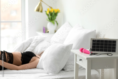 Portable solar panel charging vibrator and anal plug on table in bedroom, closeup photo