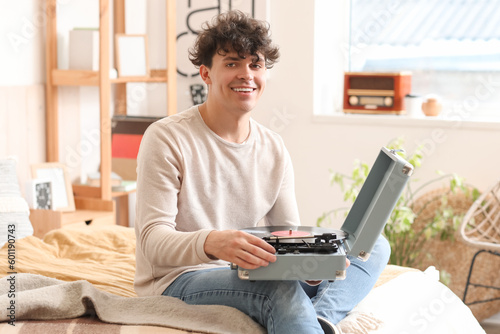 Young man with record player in bedroom