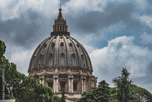Imponująca kopuła Bazyliki Świętego Piotra w Rzymie, widziana z perspektywy Muzeum Watykańskiego. Masywne i majestatyczne struktury są symbolem historycznej i religijnej potęgi Watykanu.