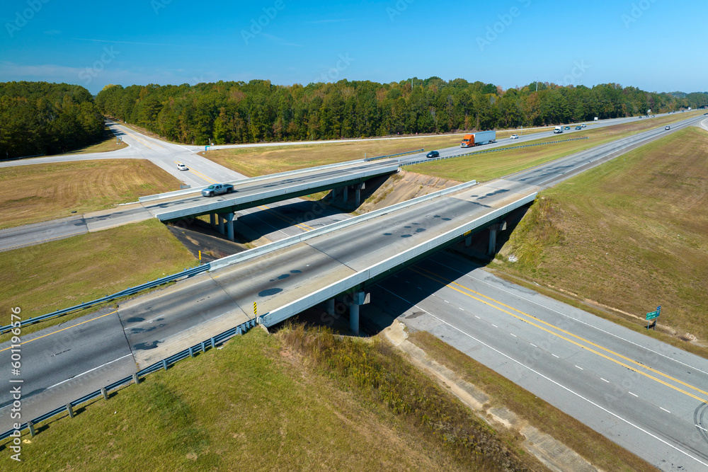 Aerial view of freeway overpass junction with fast moving traffic cars and trucks in american rural area. Interstate transportation infrastructure in USA Aerial view of freeway overpass junction with fast moving traffic cars and trucks in american rural area. Interstate transportation infrastructure in USA