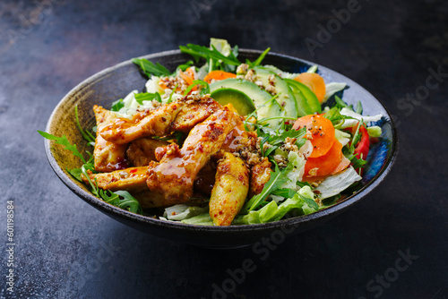 Traditional German iceberg and Italian arugula salad served with chicken, avocado and vegetables with spicy sweet and sour curry sauce as a creative and flavorful meal on a plate with text space