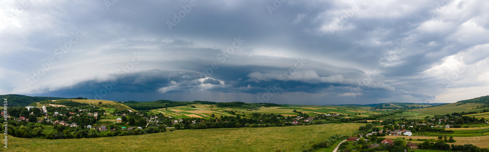 Landscape of dark clouds forming on stormy sky during thunderstorm over rural area